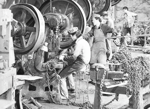 Operators crafting heavy chain components on industrial machinery